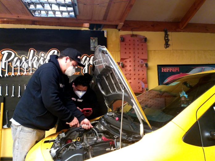 María José y Max, ambos trabajando en su taller mecánico.